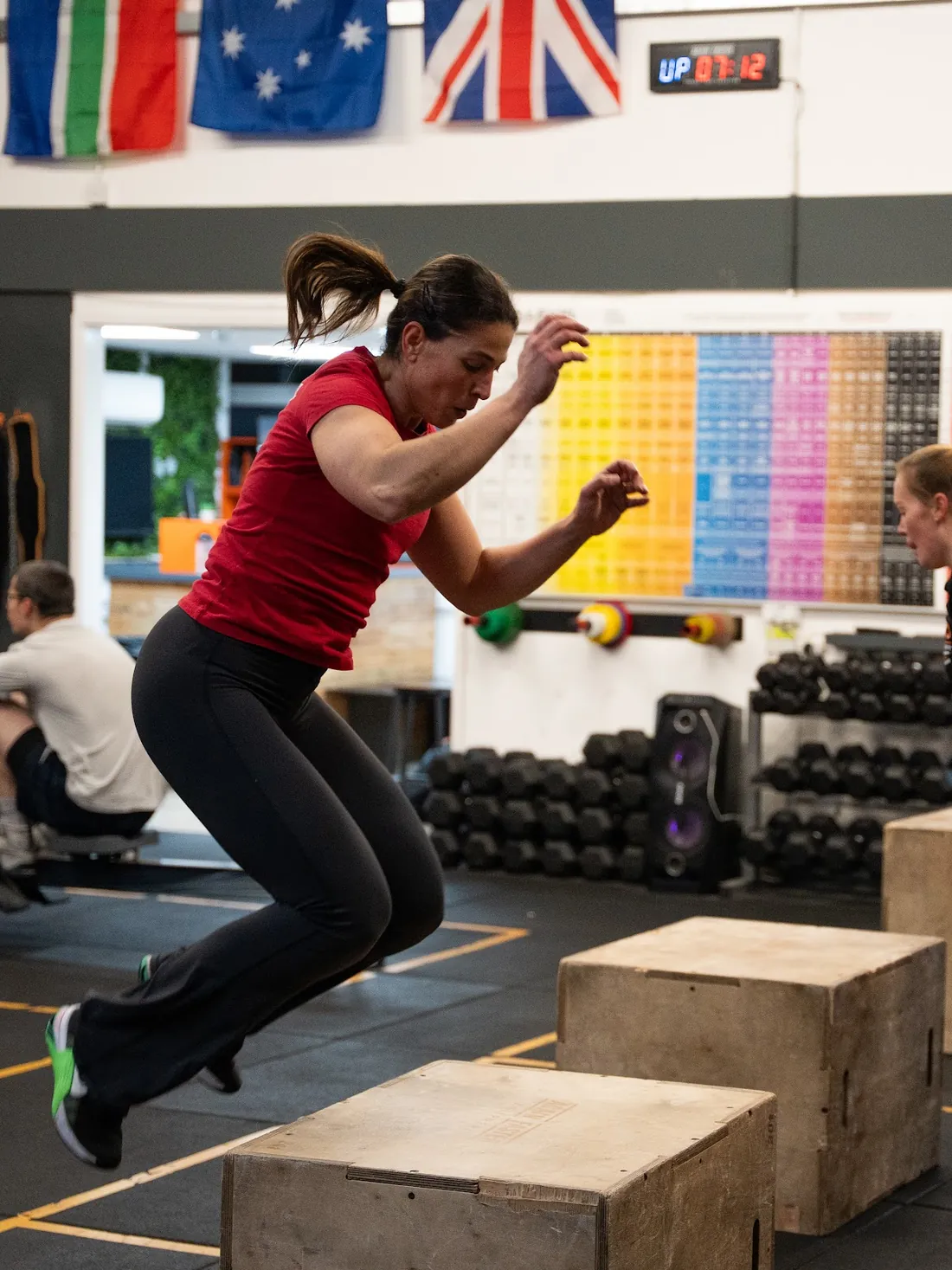 Two members mid box jump during a workout