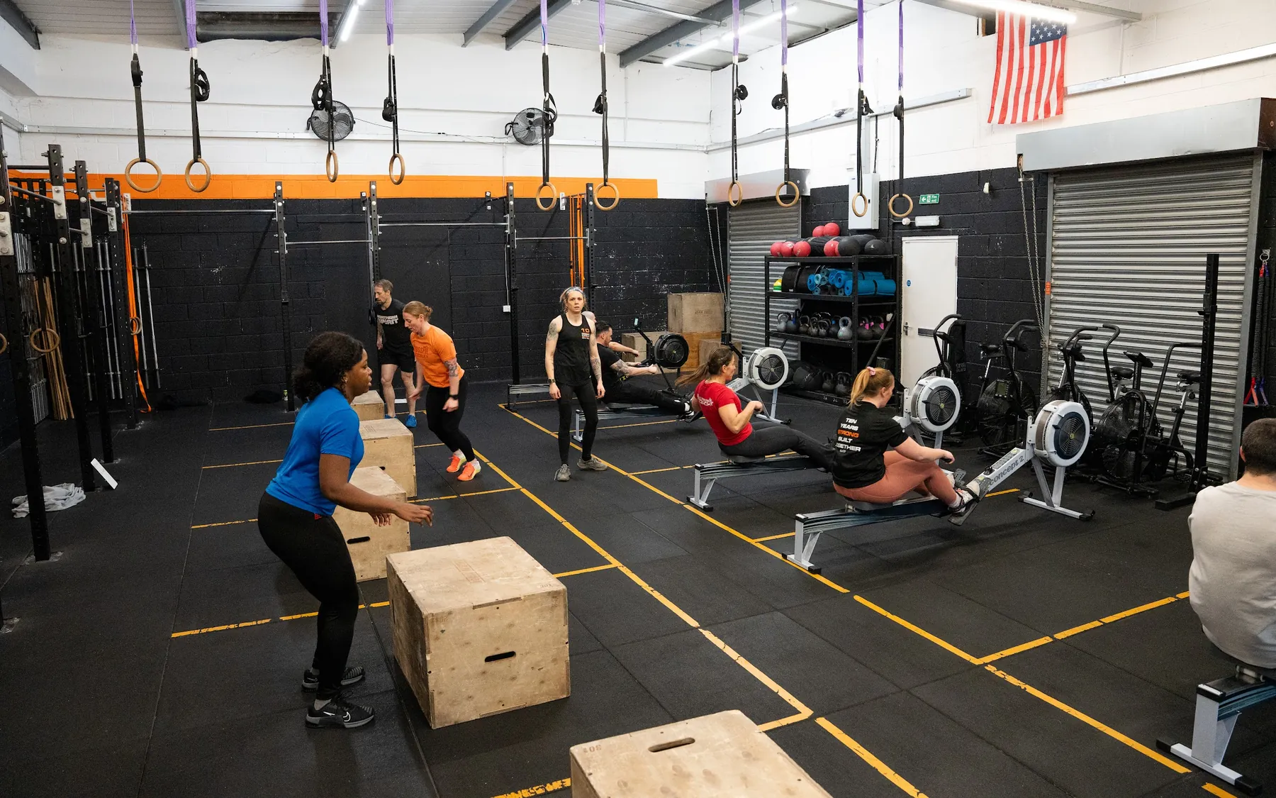 The main floor at CrossFit Bletchley during a class, with rowers, plyo boxes and the rig